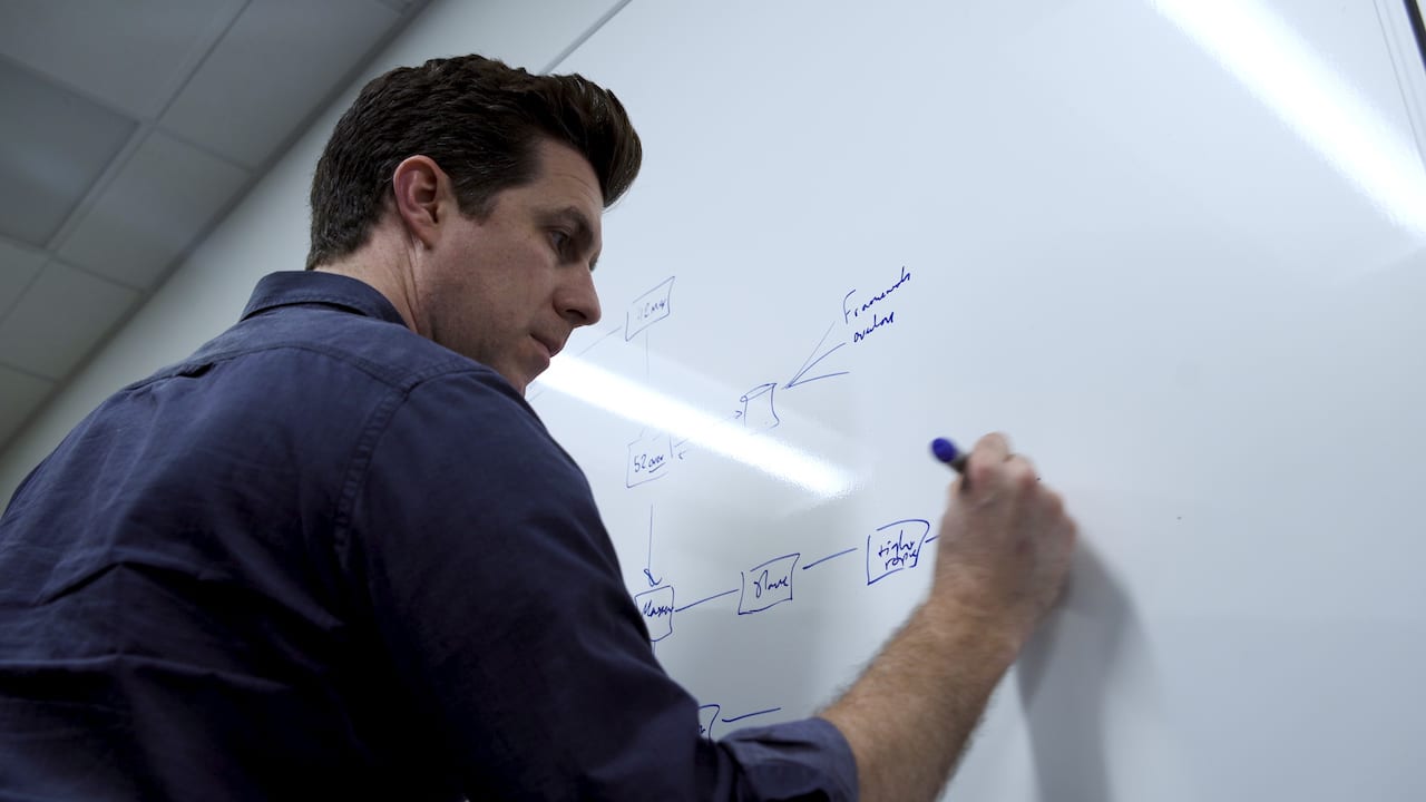 Shawn Livermore drawing system architecture and dependency diagrams at a whiteboard